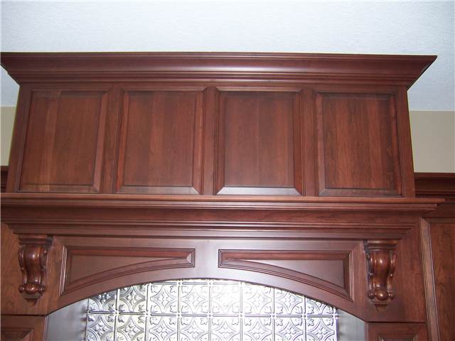 Custom wood range vent hood with raised panels and corbels